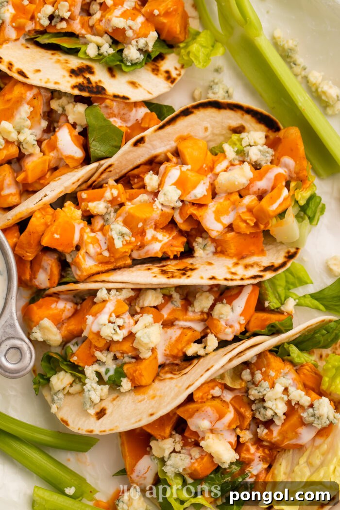 Close-up view of buffalo chicken tacos on a platter with celery and blue cheese dressing.