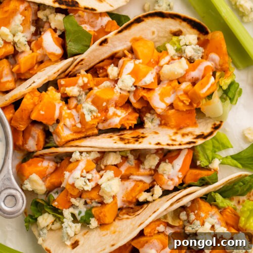 Close-up view of buffalo chicken tacos on a platter with celery and blue cheese dressing.