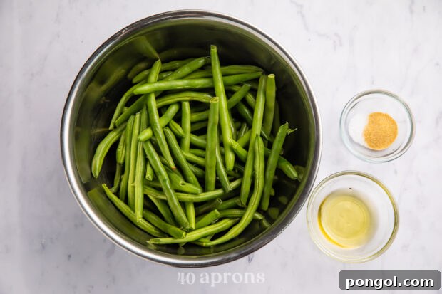 Overhead view of ingredients for air fryer green beans in bowls on white counter.