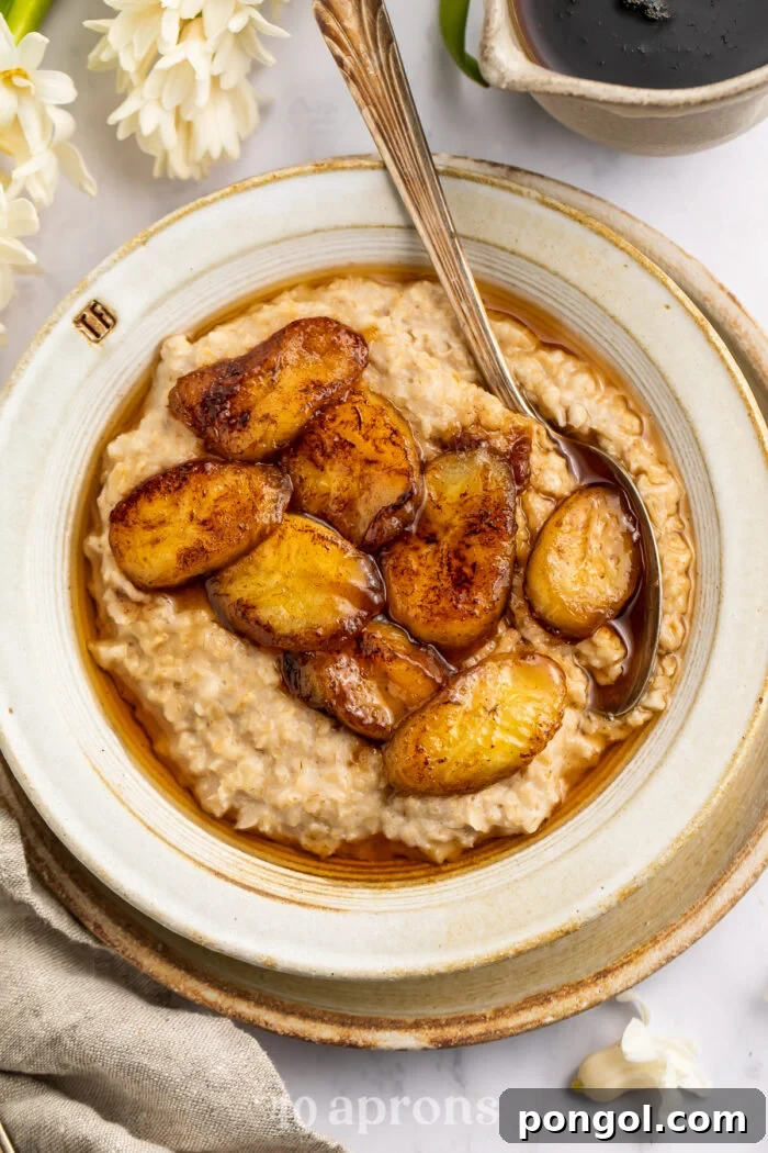 Overhead view of caramelized banana oatmeal in a white bowl on a neutral charger plate.