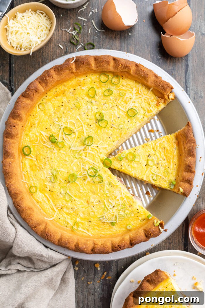 Overhead view of keto quiche in a pie crust plate, with one slice of quiche missing and another separated from the rest.