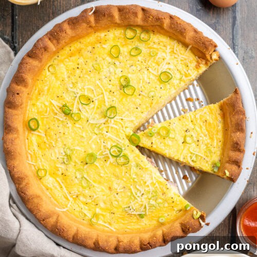 Overhead view of keto quiche in a pie crust plate, with one slice of quiche missing and another separated from the rest.