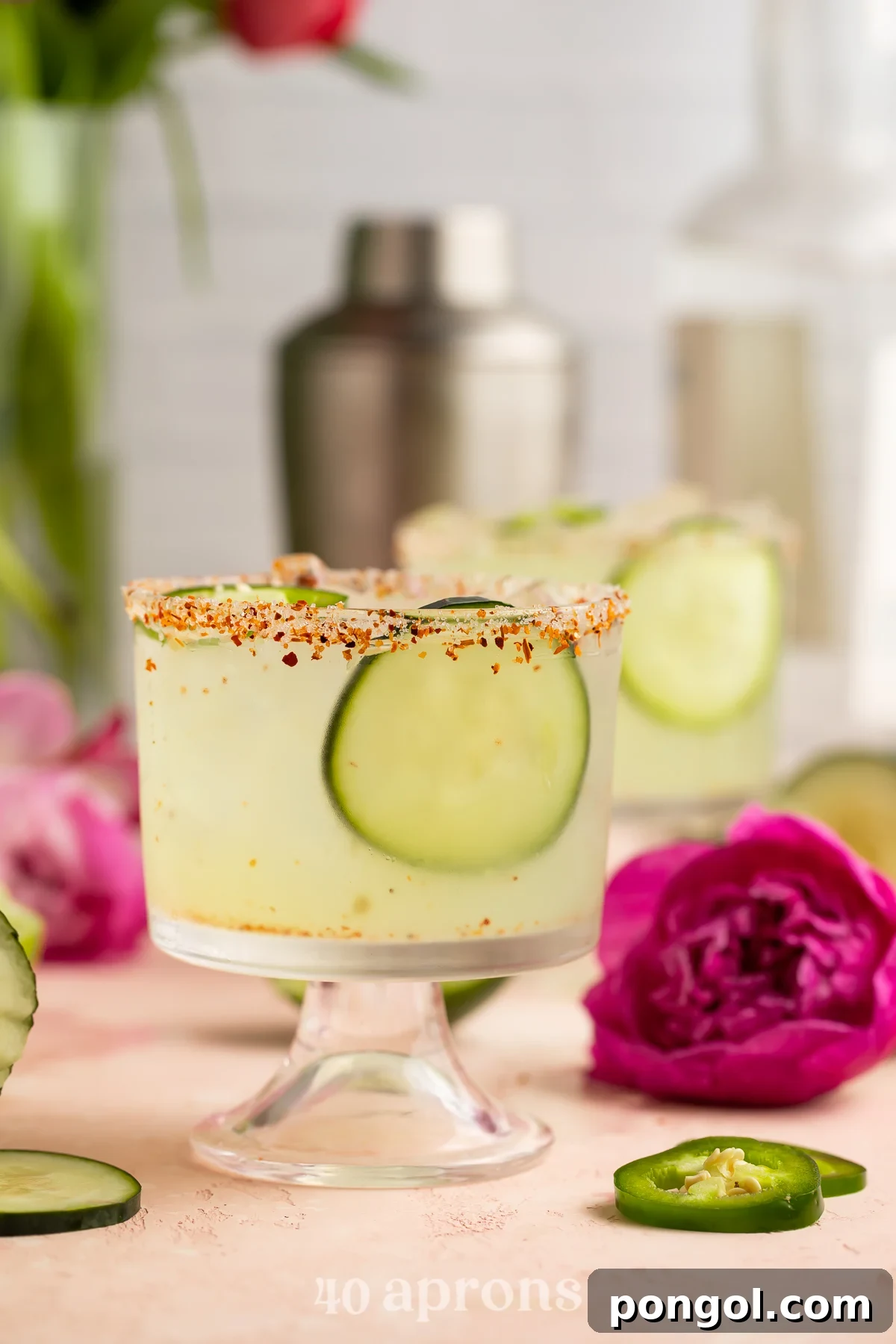 Jalapeño Cucumber Zing Margarita 2 A refreshing cucumber jalapeno margarita in a short glass, garnished with fresh cucumber slices and a vibrant fuschia flower.
