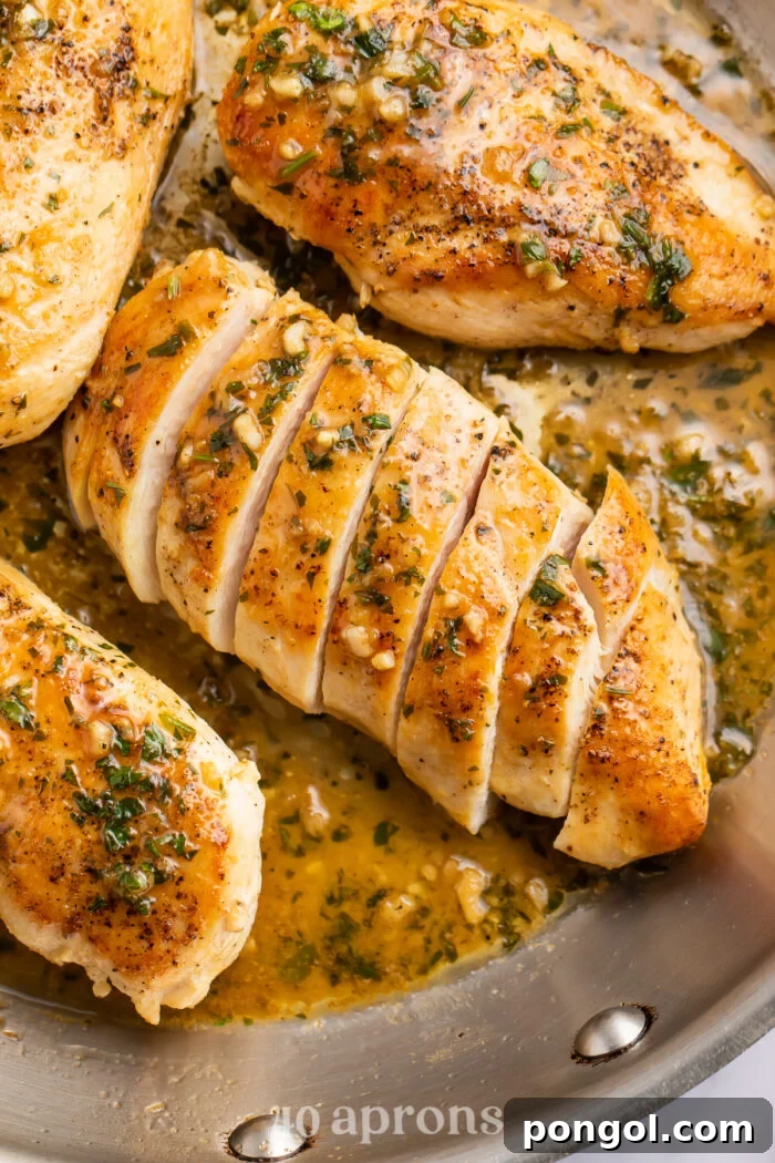 Overhead view of a garlic butter chicken breast sliced diagonally into strips on a skillet.