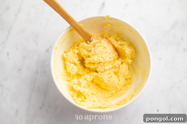 Overhead view of garlic butter sauce mixture in a white bowl with a wooden spoon.