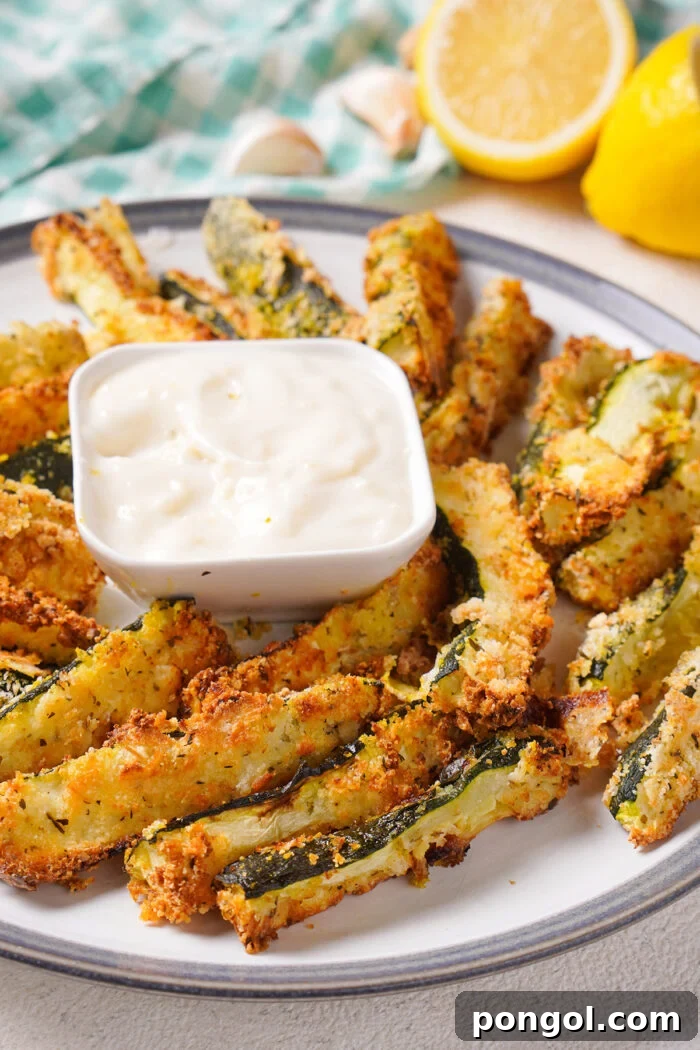 Side view of a plate of air fryer zucchini with lemons in the background.