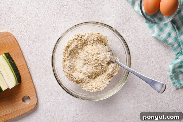 Overhead view of breadcrumb mixture in a medium glass mixing bowl with a fork.