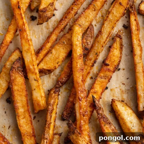 Close-up view of cajun fries on a baking sheet lined with parchment paper, freshly baked.