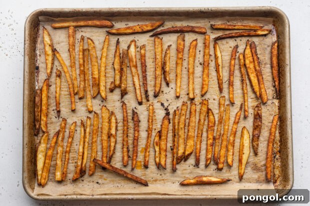 Overhead view of seasoned cajun fries on a baking sheet lined with parchment paper.
