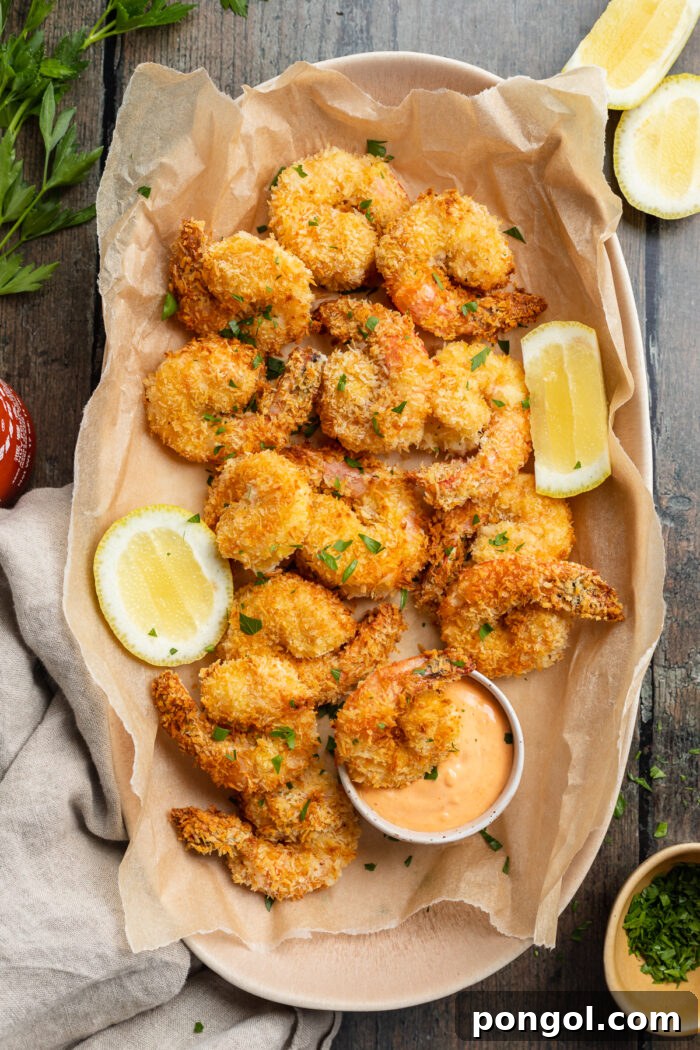 Overhead view of a platter of air fryer fried shrimp with sriracha mayo and lemon coins.