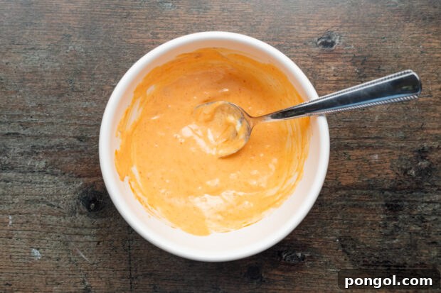 Overhead view of sriracha mayo in a bowl with a spoon.