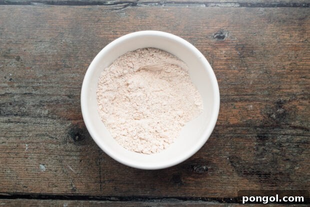 Overhead view of all-purpose flour and Old Bay seasoning mixed together in a white mixing bowl.