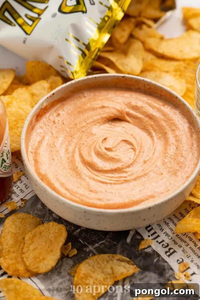 Decadent Cajun Cream Sauce 3 Side view of a bowl of creamy Cajun sauce, garnished with a sprinkle of paprika, and surrounded by a variety of Zapp's potato chips, showcasing its rich texture and perfect consistency.