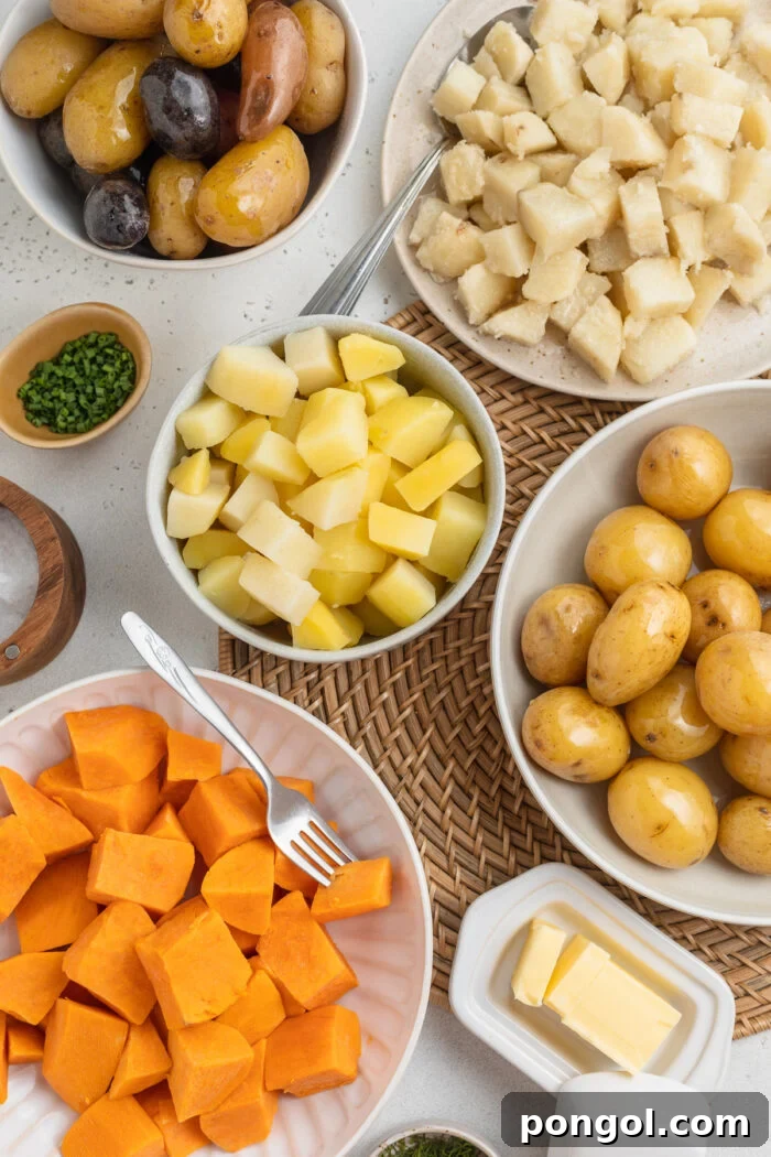 Overhead view of several varieties of boiled potatoes in bowls arranged together on a table.