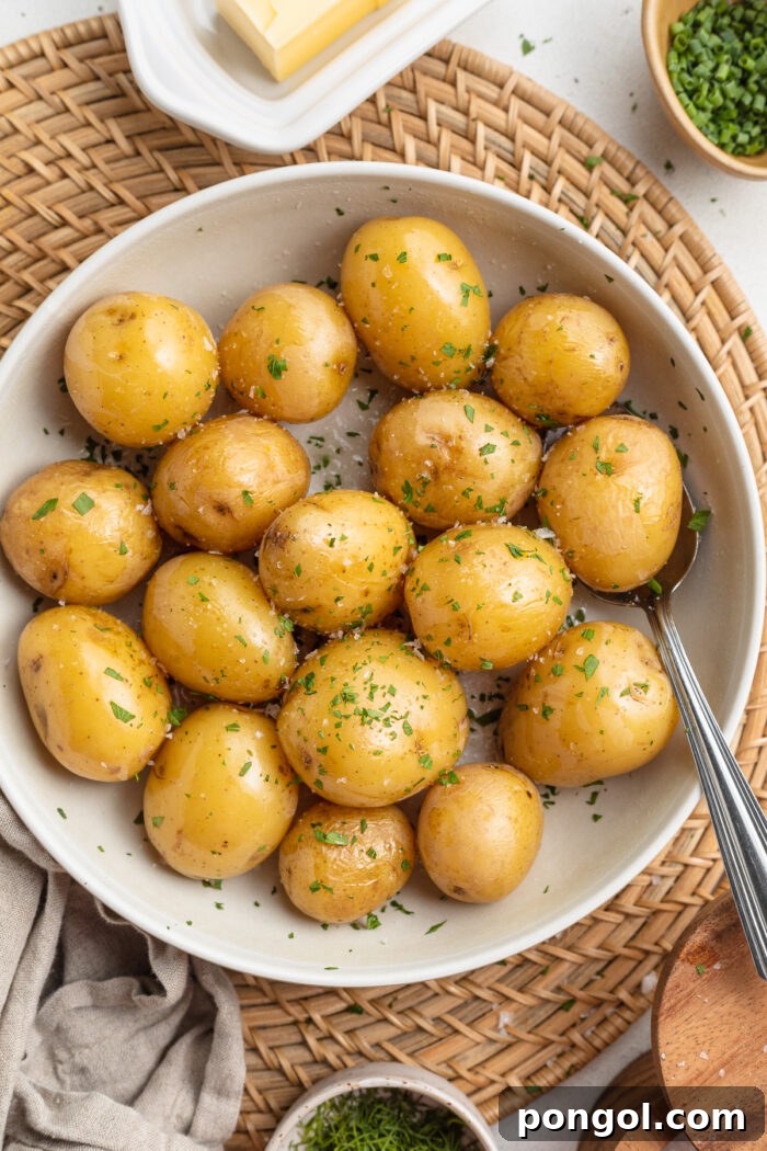 Overhead, zoomed out view of a bowl of boiled baby potatoes with rosemary and garlic in a bowl.