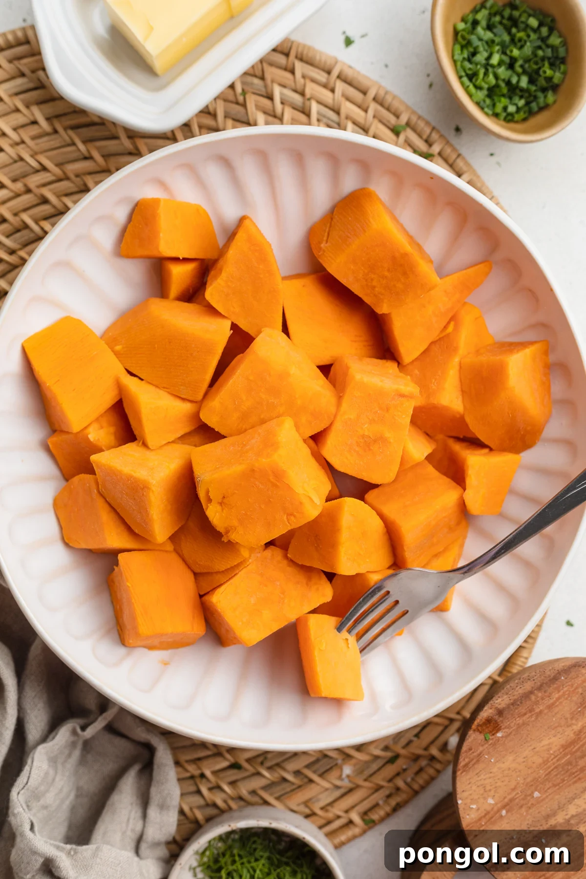 Close-up view of boiled baby potatoes seasoned with garlic and rosemary, with a sprig of fresh rosemary on top.