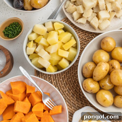 Overhead view of several varieties of boiled potatoes in bowls arranged together on a table.