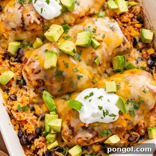 Overhead, angled view of a Mexican chicken and rice casserole with corn, black beans, sour cream, and diced avocado.