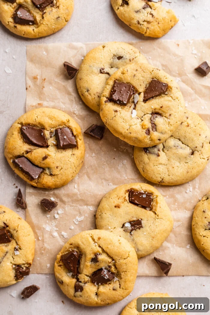 Effortless Air Fryer Chocolate Chip Cookies 2 Overhead view of air fryer chocolate chip cookies scattered on a tabletop covered in parchment paper.