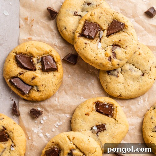 Effortless Air Fryer Chocolate Chip Cookies 4 Overhead view of air fryer chocolate chip cookies scattered on a tabletop covered in parchment paper.