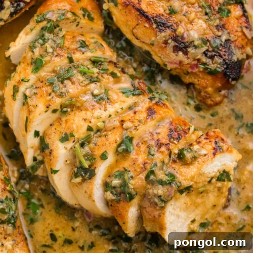 Overhead, close-up view of a sliced garlic herb butter chicken breast in garlic herb sauce in a large silver skillet.