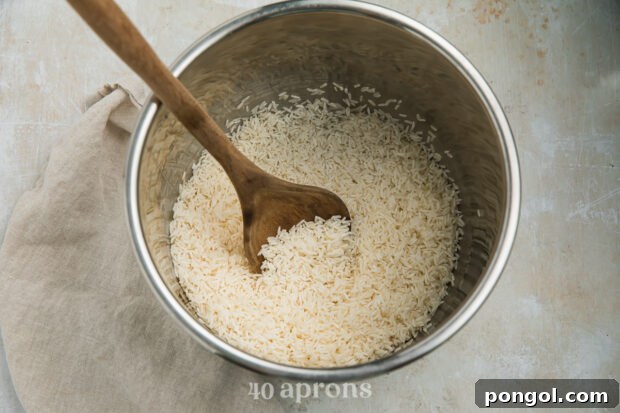 Overhead view of long grain rice in the Instant Pot insert with a wooden spoon.