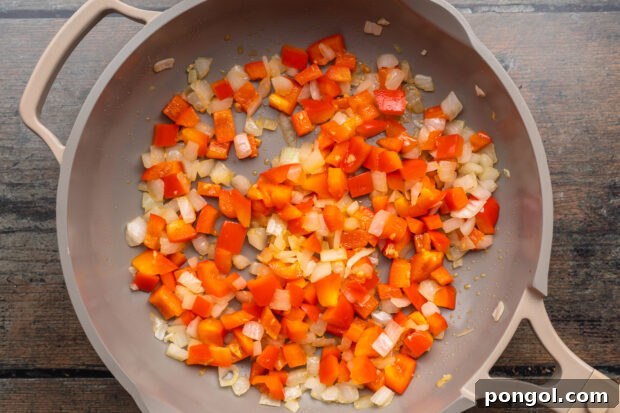 Sautéing onions, bell peppers, and garlic in a large skillet for enchilada filling.