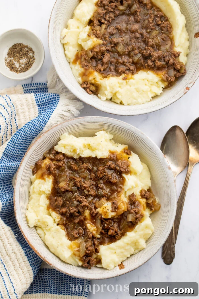 Zoomed out overhead view of a bowl of ground beef and gravy on top of fluffy, creamy mashed potatoes.