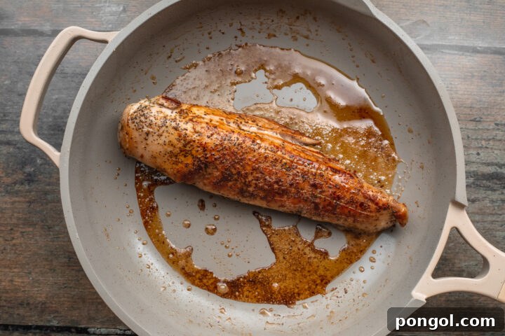 Overhead view of sous vide pork tenderloin in a large skillet, seared until golden brown on top.