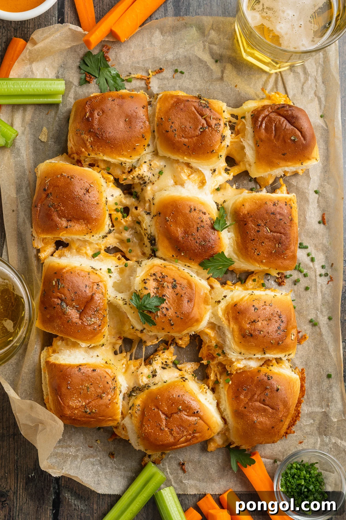 Spicy Buffalo Chicken Minis 3 Zoomed out, overhead view of one dozen buffalo chicken sliders arranged in 4 rows of 3 on a wooden table.