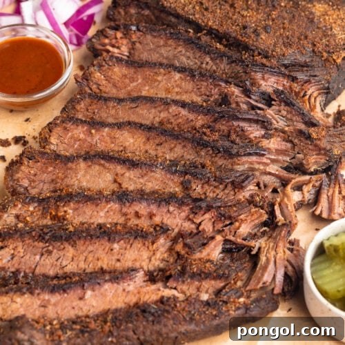 Sous vide brisket, sliced thin and arranged on a wooden serving tray with seasoning and garnish.
