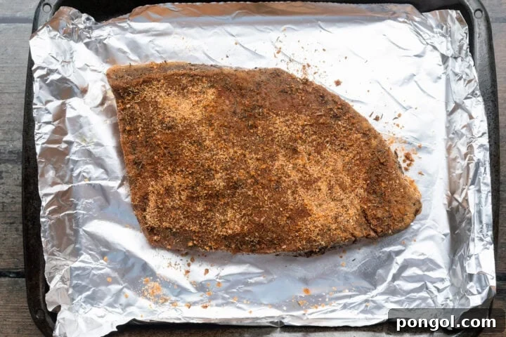 Seasoned sous vide brisket on a sheet pan lined with aluminum foil.