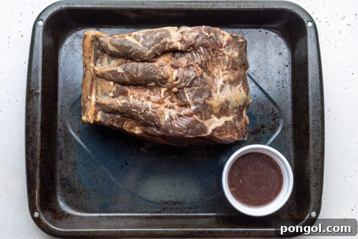 Overhead view of sous vide prime rib on a roasting pan with small ramekin of reserved juices.