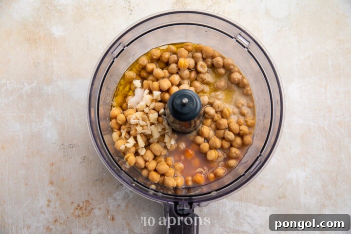 Overhead view of all buffalo hummus ingredients in a food processor bowl (uncovered) before processing.