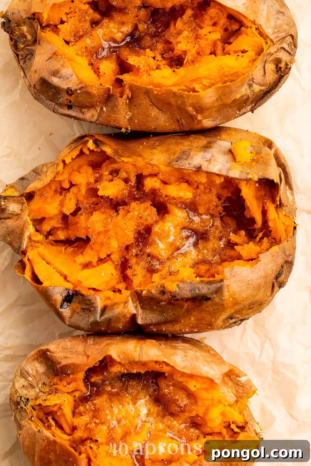Overhead view of a vertical row of cut-open sweet potatoes on a sheet of parchment paper.