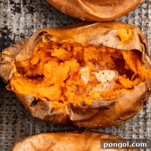 Overhead view of a vertical row of cut-open sweet potatoes on a sheet of foil.
