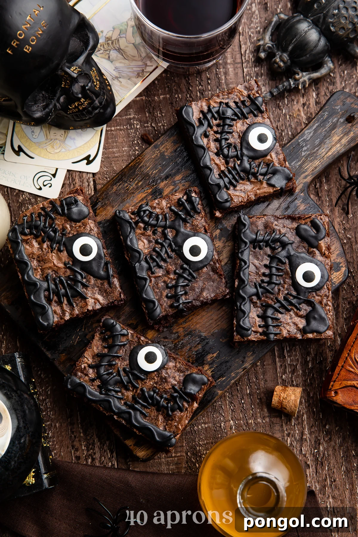 Overhead view of 5 Hocus Pocus spellbook brownies on a wooden tray surrounded by Halloween imagery, including fall leaves and mini pumpkins.