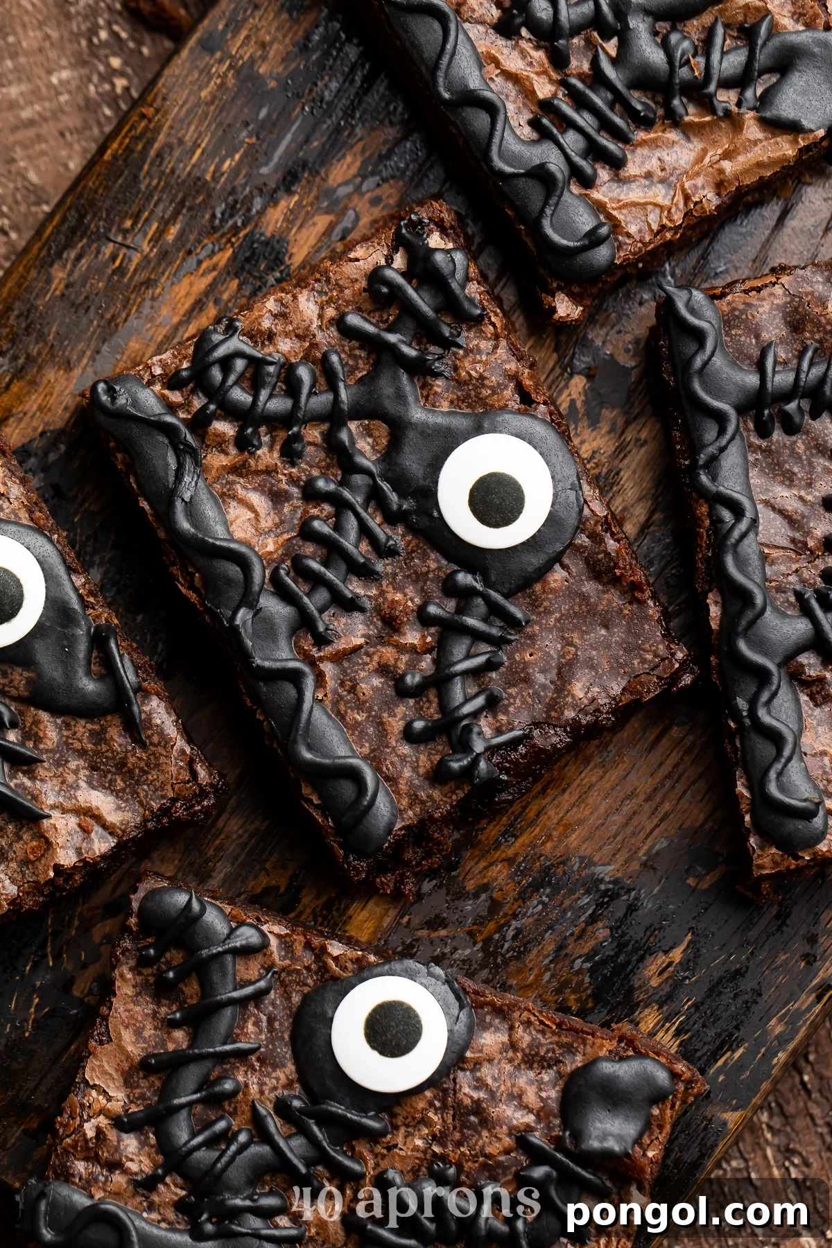 Close-up of one Hocus Pocus spellbook brownie out of 5 on a wooden tray, showing intricate icing details and a candy eye.