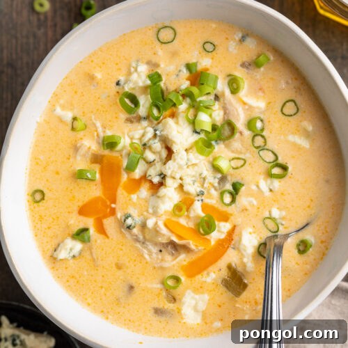 Overhead view of buffalo chicken soup in a misshapen round bowl on a wooden table.