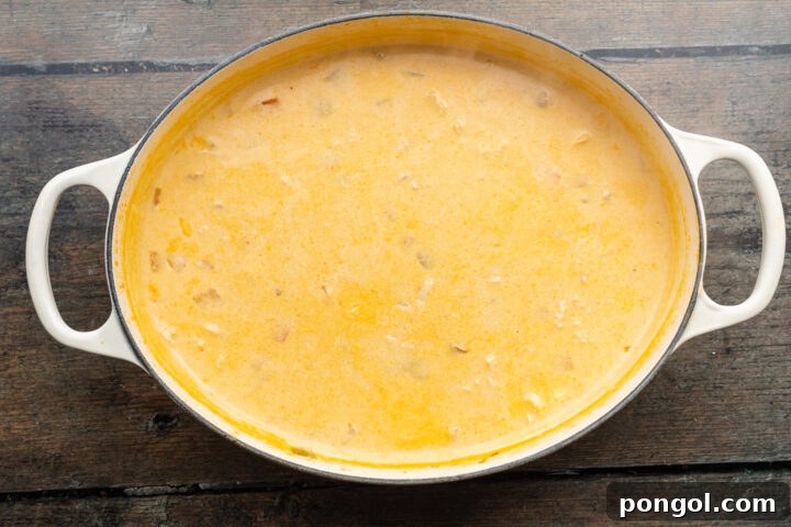 Overhead view of rich, creamy buffalo chicken soup in a large pot, ready to serve, on a wooden table.