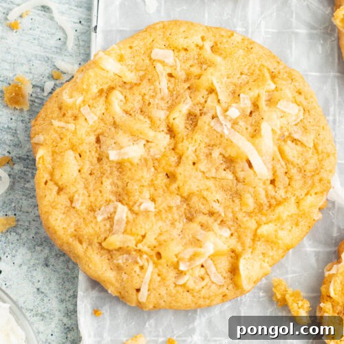 Overhead view of delicious coconut cookies on a table next to a glass of coconut milk.
