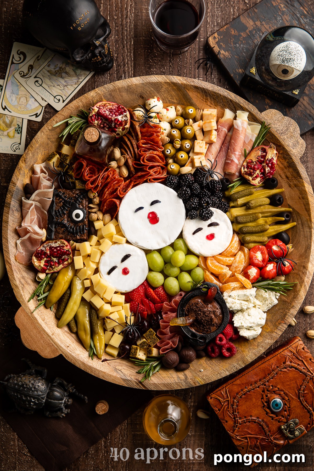 Close-up overhead view of the Hocus Pocus charcuterie board, highlighting the brie cheese faces of the Sanderson Sisters and the arrangement of surrounding fruits and snacks.