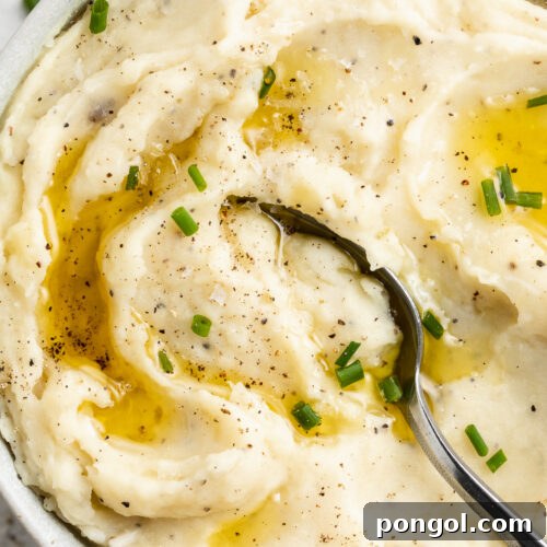 Velvety Vegan Mashed Potatoes 4 Close-up, overhead view of a large white bowl holding dairy-free mashed potatoes topped with brown gravy.