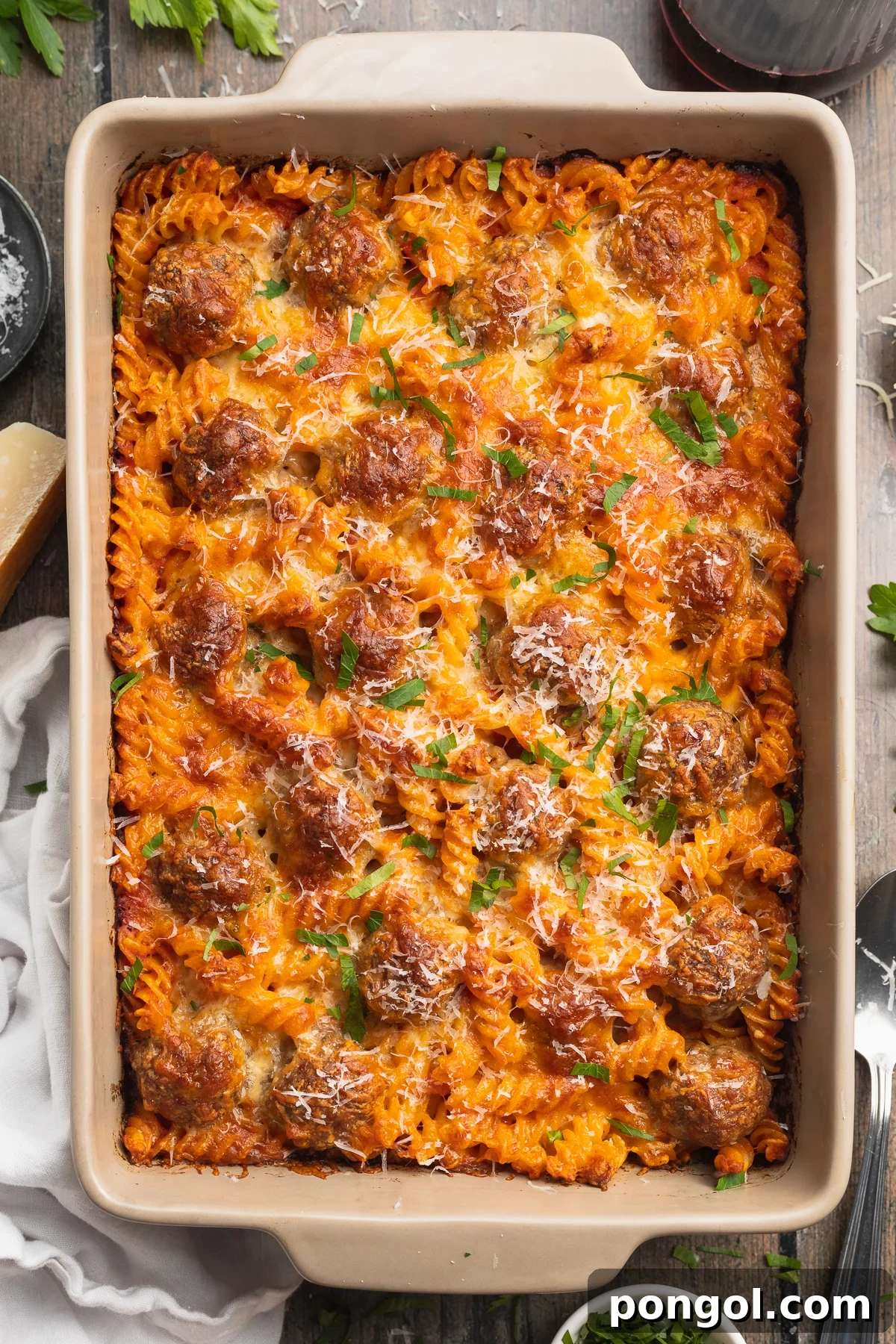 Overhead view of a large pan of meatball casserole with rotini pasta and cheese.