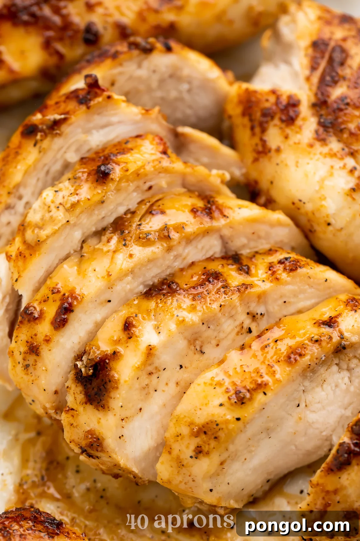 Air fryer frozen chicken breast sliced thin and lined up on a cutting board.