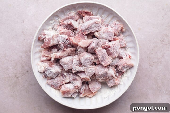 Chopped pork shoulder coated in flour resting on a plate.
