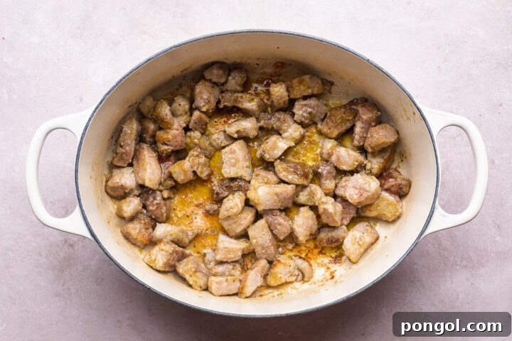 Overhead view of pork shoulder in a large oval dutch oven.