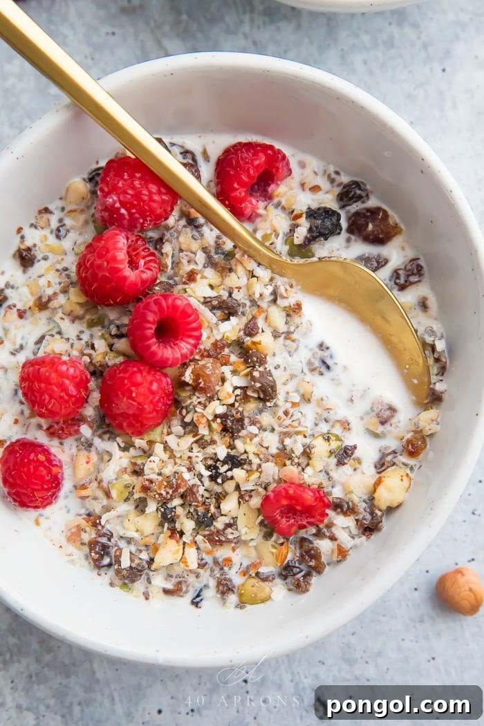 A bowl of paleo cereal with a gold spoon and raspberries on top