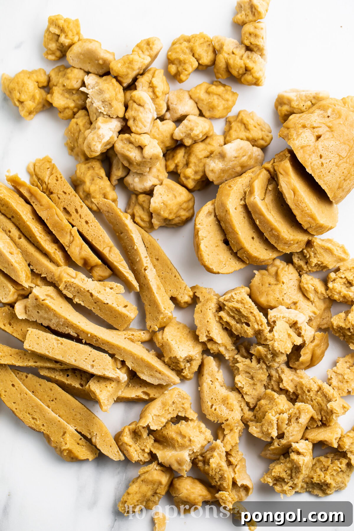 An inviting overhead view showcasing four distinct preparations of seitan on a elegant marble countertop, illustrating its versatility.