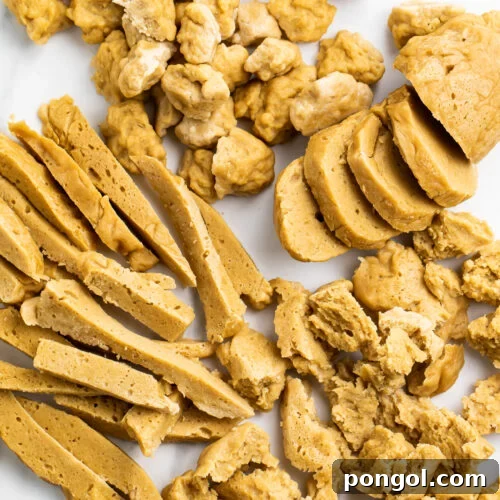 Overhead view of 4 different types of seitan on a marble countertop.